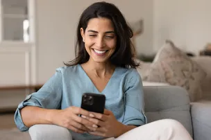 Mulher olhando para o celular com expressão sorridente